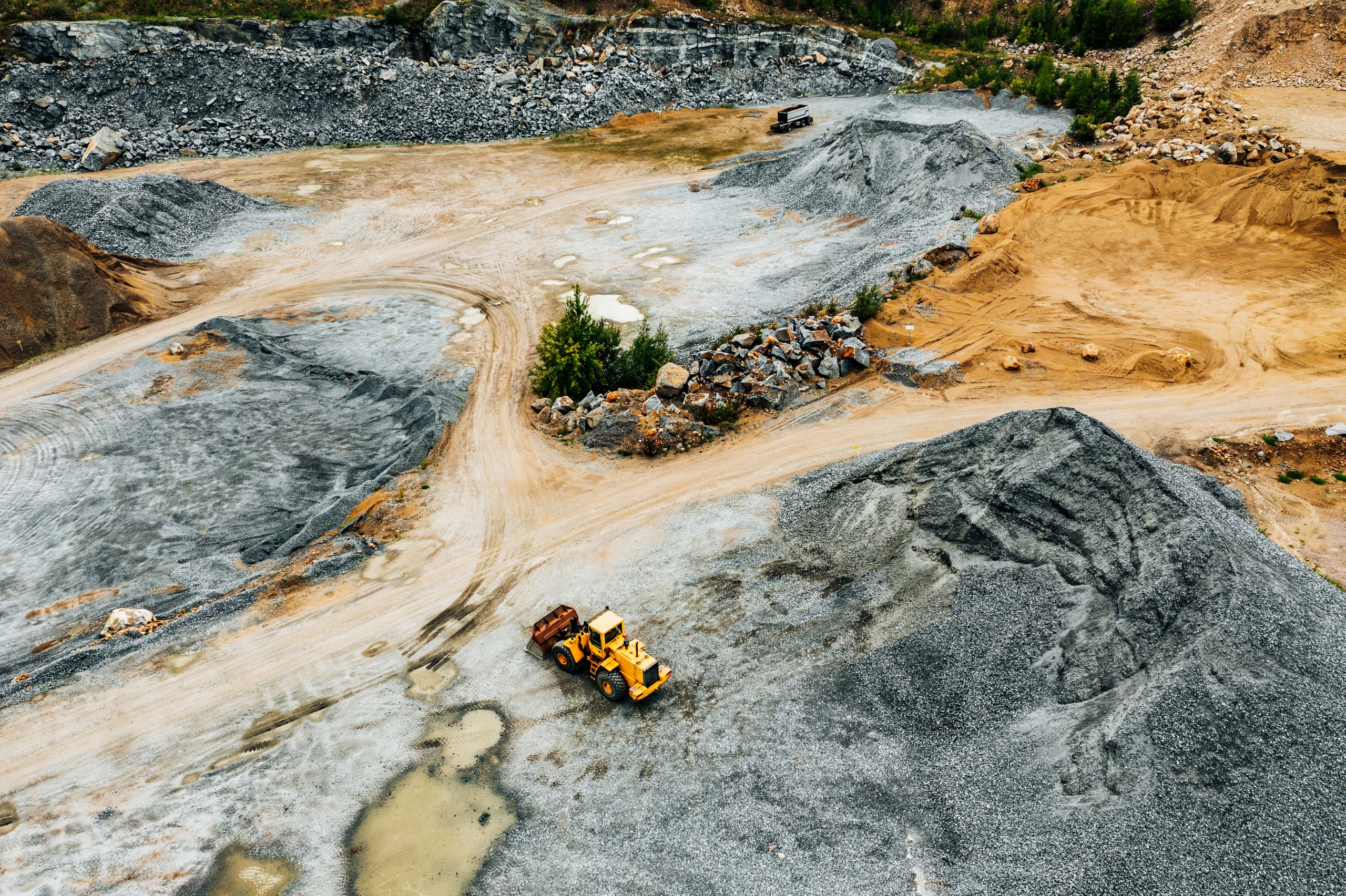 Aerial view of Truck excavator in open sand quarry rubble.