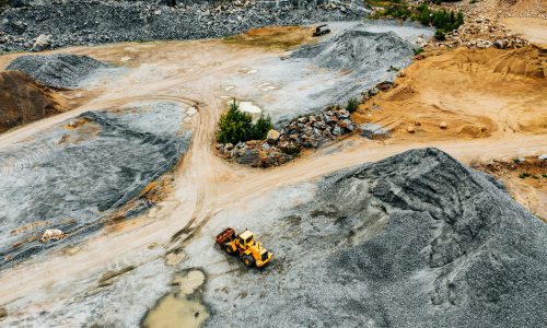 Aerial view of Truck excavator in open sand quarry rubble.